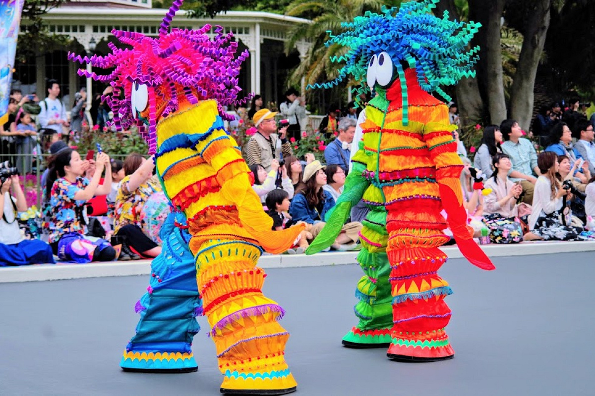 花や鳥モチーフの衣装のダンサーたちの後ろを歩く モメラス キャステル Castel ディズニー情報